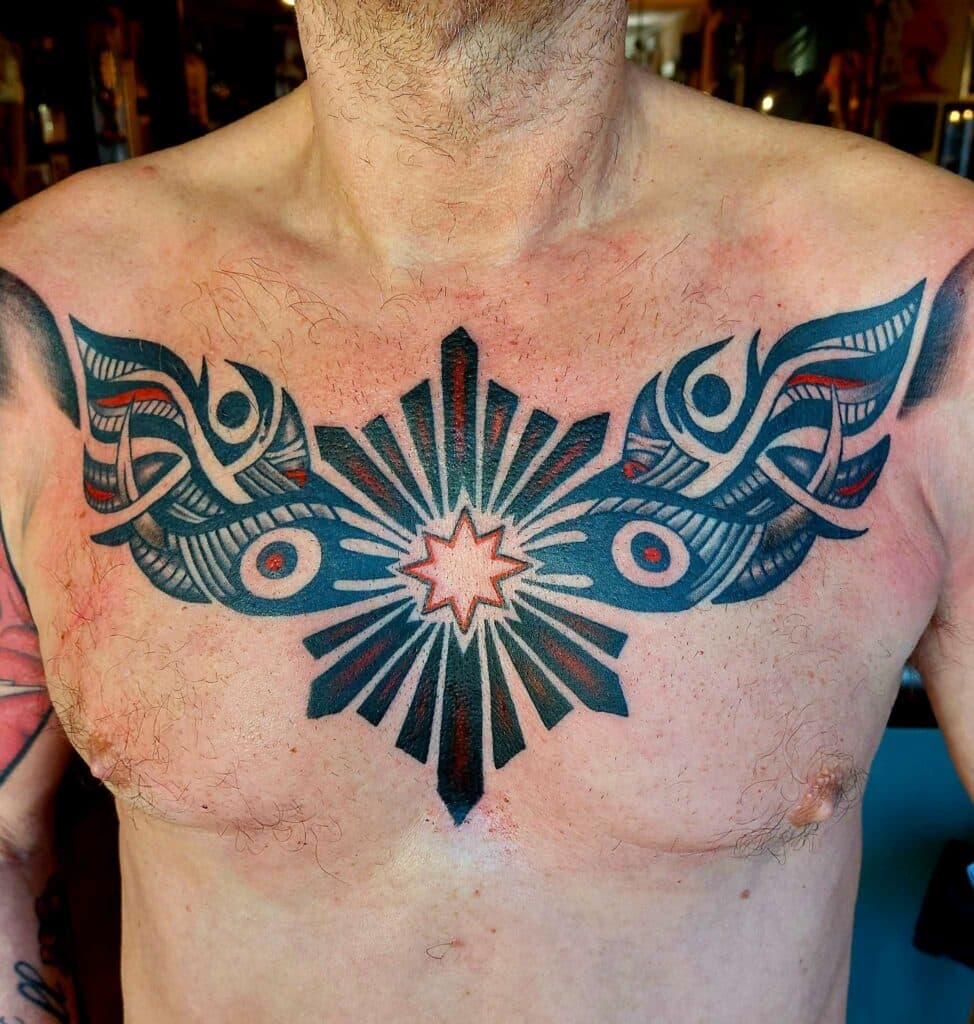 Grote symmetrische borst tattoo met geometrische patronen, vleugels en een ster.