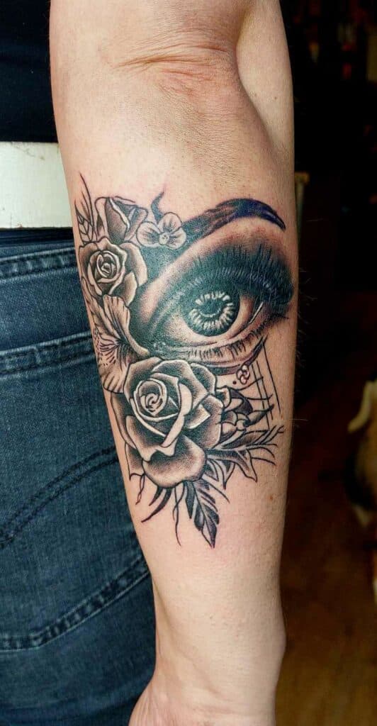 Realistisch oog met rozen en bloemen op onderarm.