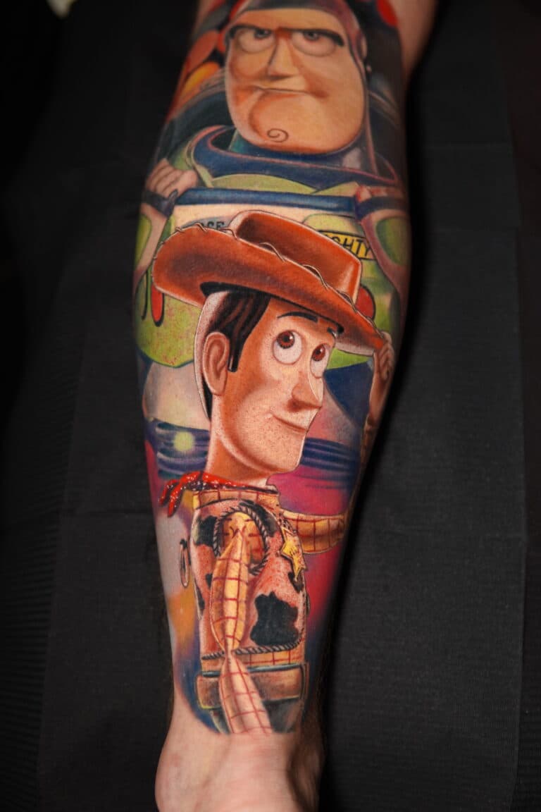 Realistische Toy Story tattoo van Woody en Buzz Lightyear op een onderbeen.