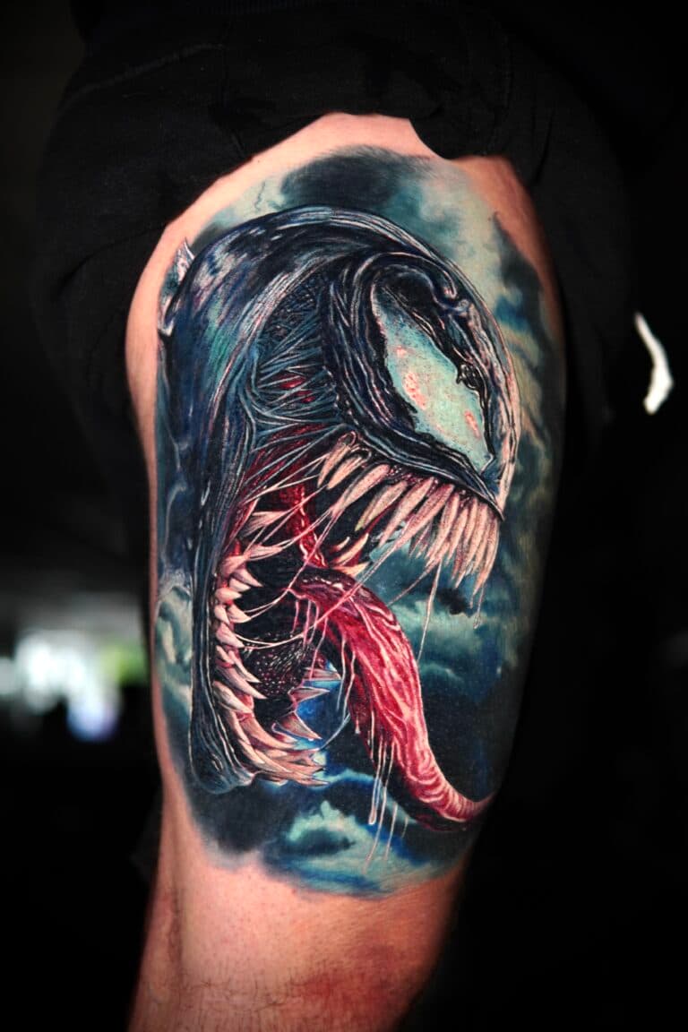 Realistische Venom tattoo met open mond en tong op bovenbeen.
