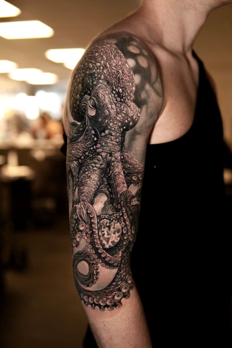 Gedetailleerde realistische octopus tattoo op bovenarm en schouder.