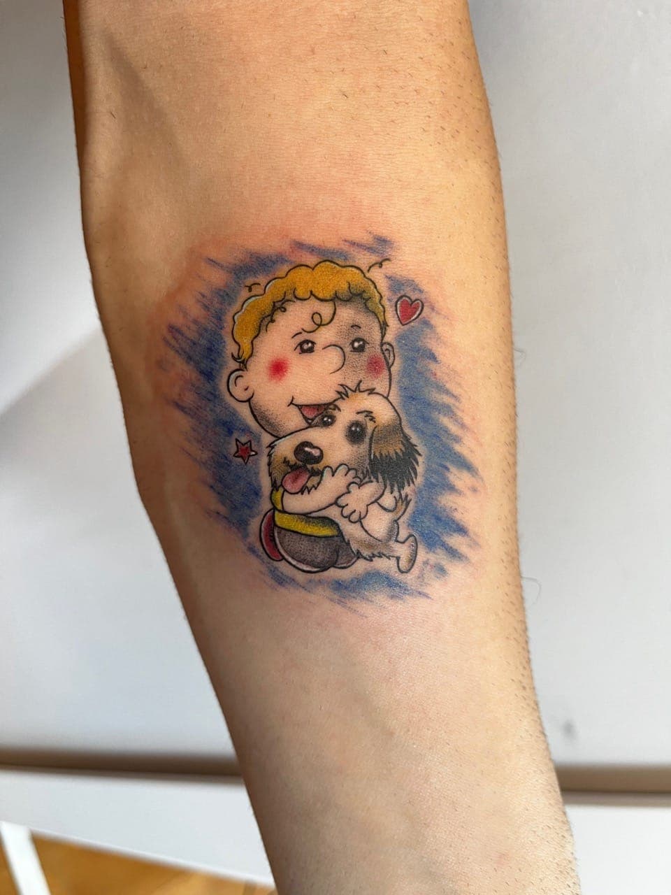 Kleurrijke cartoon tattoo van een jongen die een hond knuffelt.