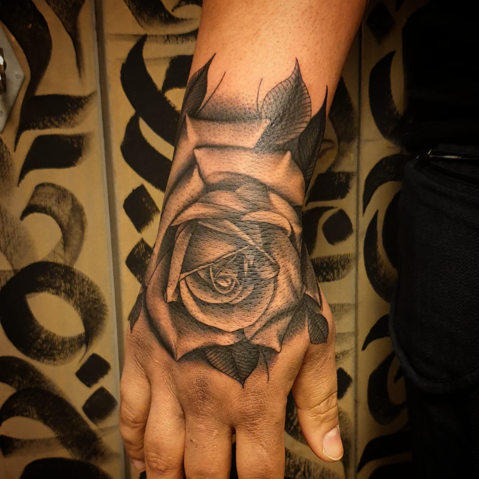 Realistische roos tattoo op de hand in zwart-wit.