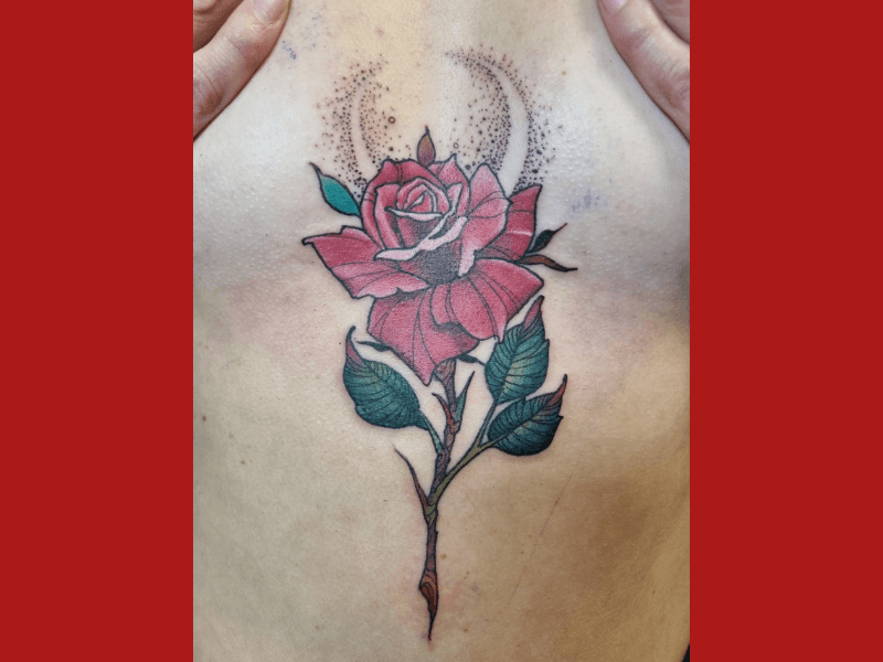 Neo-traditional rode roos met groene bladeren en dotwork maan op het borstbeen.