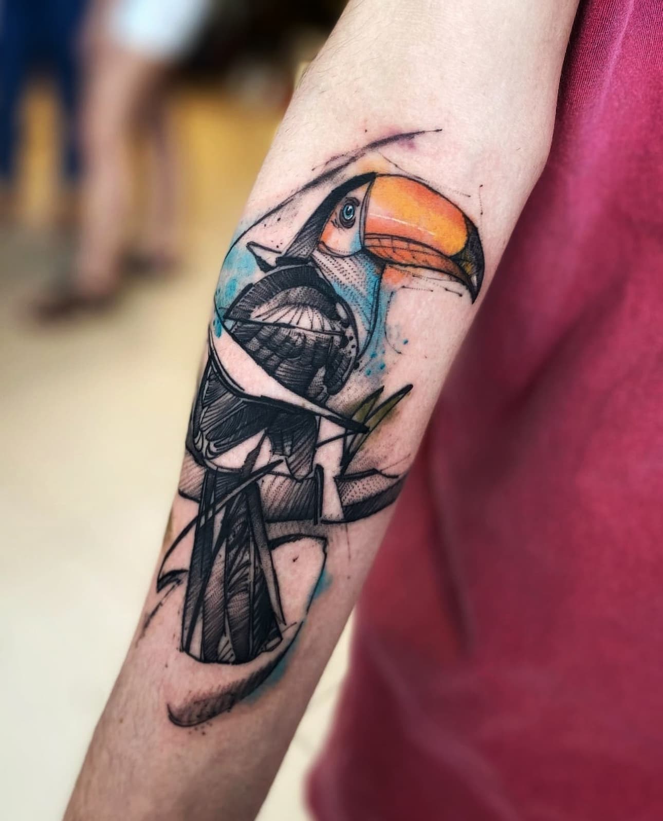 Kleurrijke aquarel en schets tattoo van een toekan op een tak.