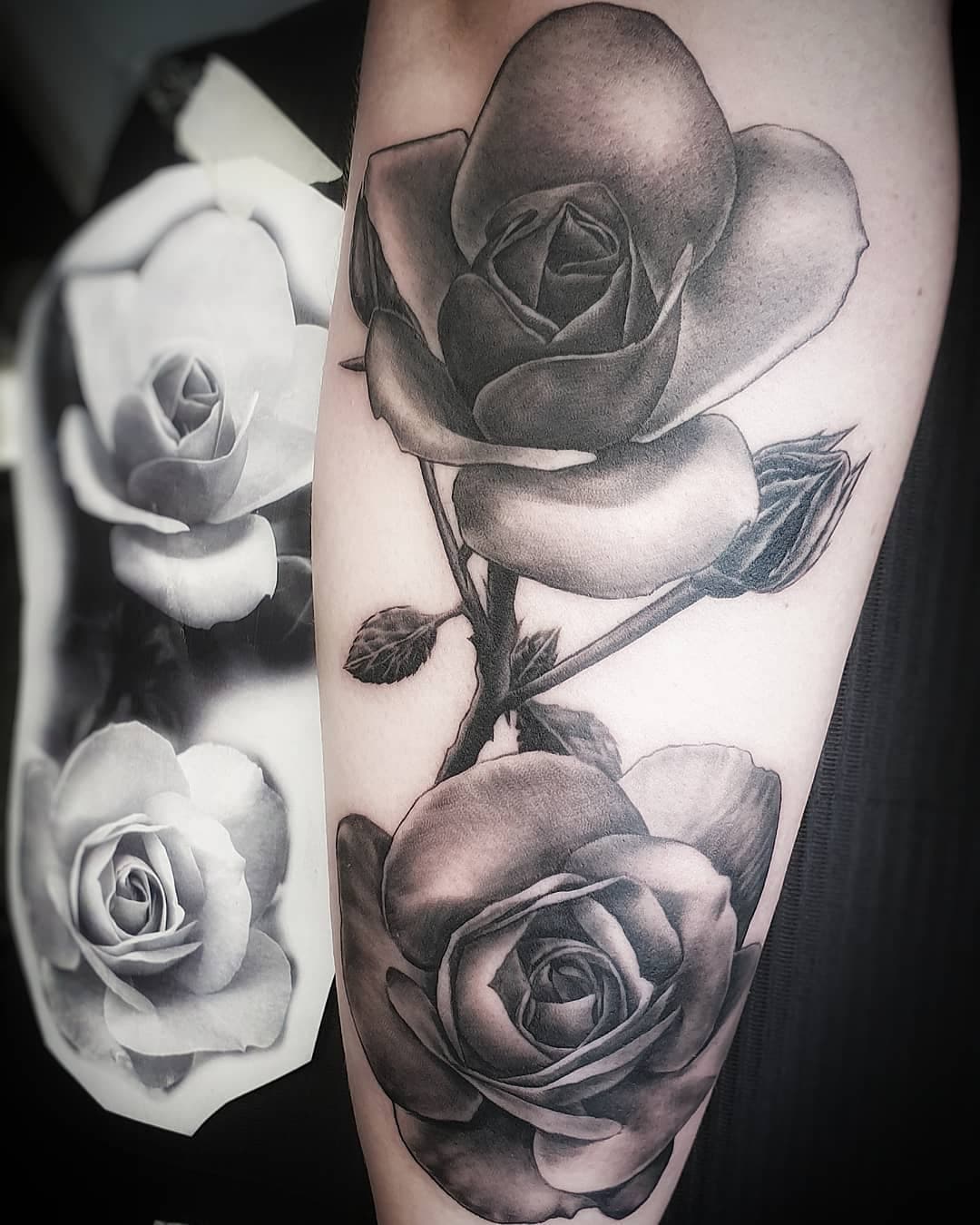 Realistische zwart-grijze rozen tattoo op de onderarm.