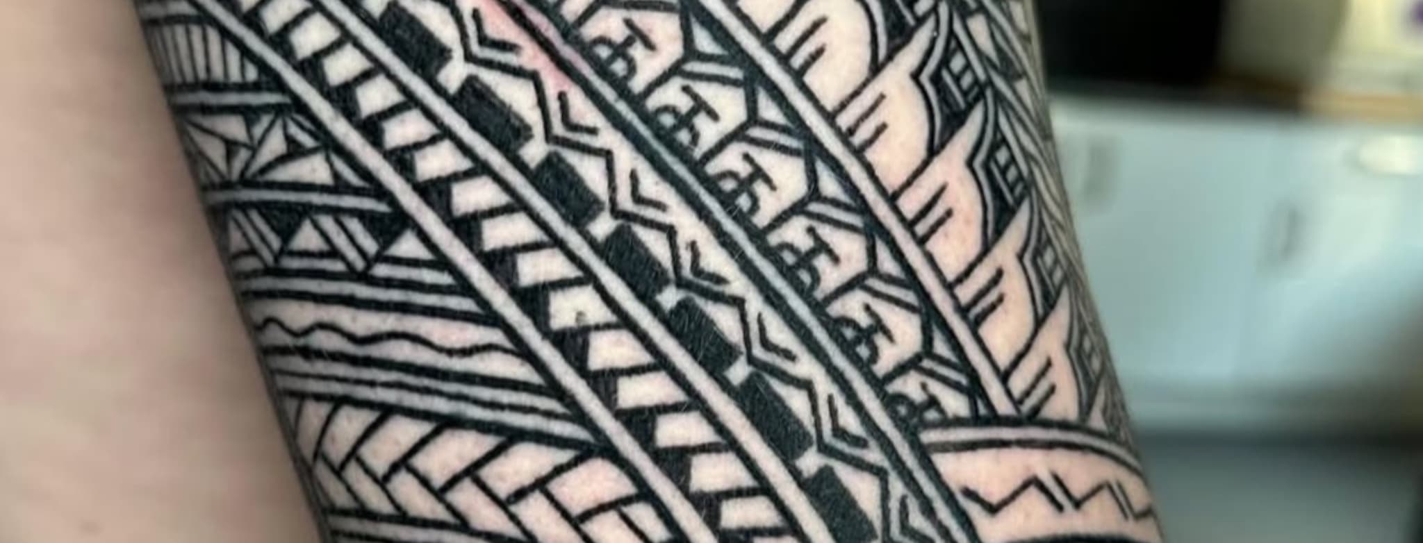 Close-up van een Polynesische tribal tattoo op de arm met geometrische patronen.