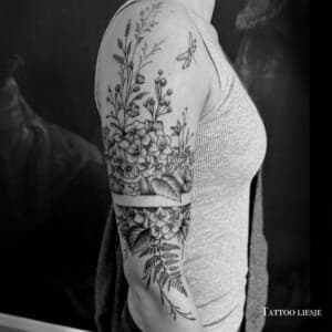 Zwart-wit fineline en dotwork bloemen half-sleeve met varen en libel.