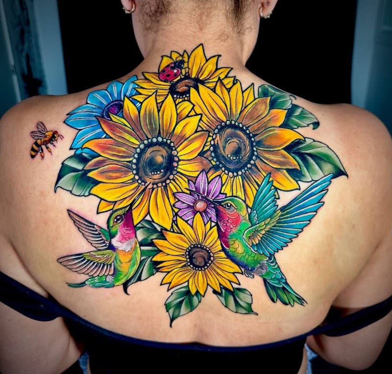 Kleurrijke tattoo van zonnebloemen, kolibries, een bij en een lieveheersbeestje.