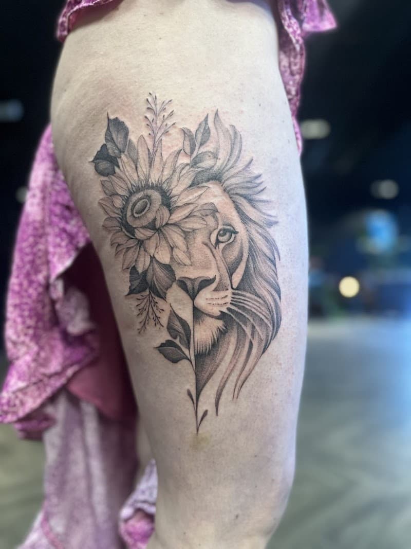 Halve leeuwenkop met zonnebloem en bladeren op bovenbeen.