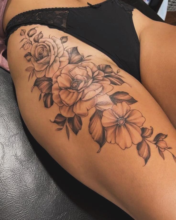 Grote zwart-wit bloemen tattoo op het bovenbeen.