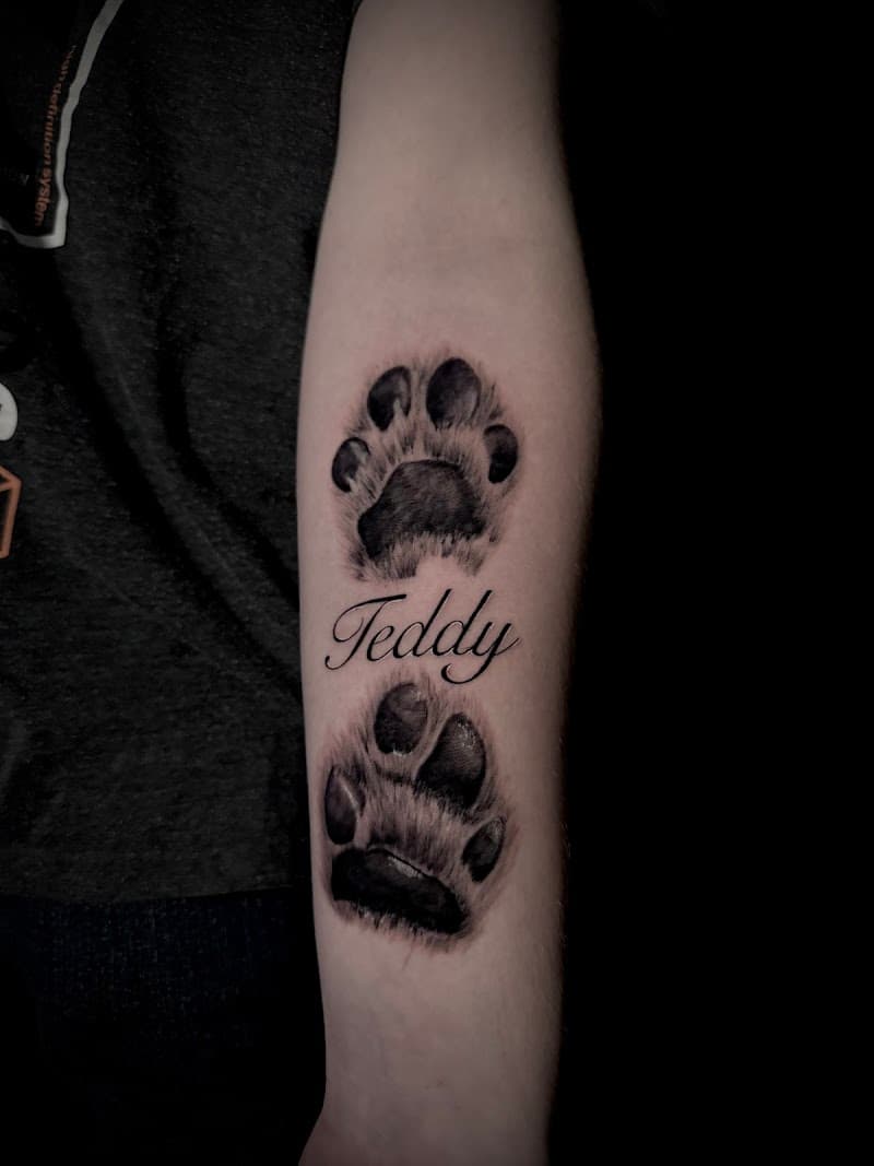 Realistische hondenpootafdrukken met de naam 'Teddy' op de onderarm.