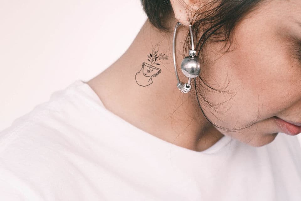 Minimalistische lijntekening van een buste met bloemen in de nek.