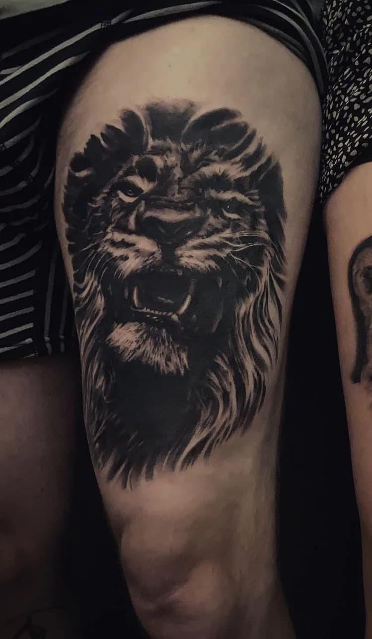 Realistische leeuwenkop tattoo op het bovenbeen.