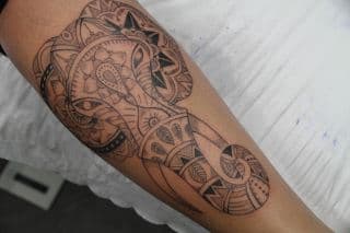 Gedetailleerde olifant tattoo met mandala patronen op onderbeen.