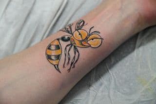 Cartoon wesp tattoo op onderarm, boze blik.