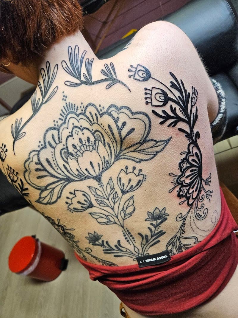 Grote rugtattoo met bloemen en bladeren in een illustratieve, folk-art stijl.