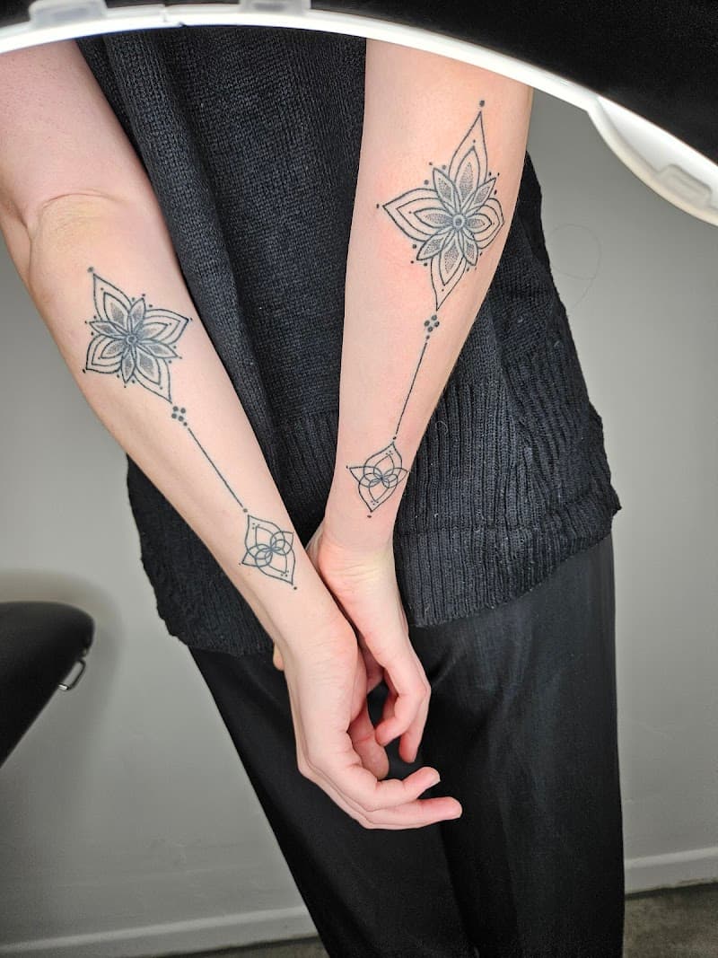 Symmetrische geometrische mandala tattoos op beide onderarmen.