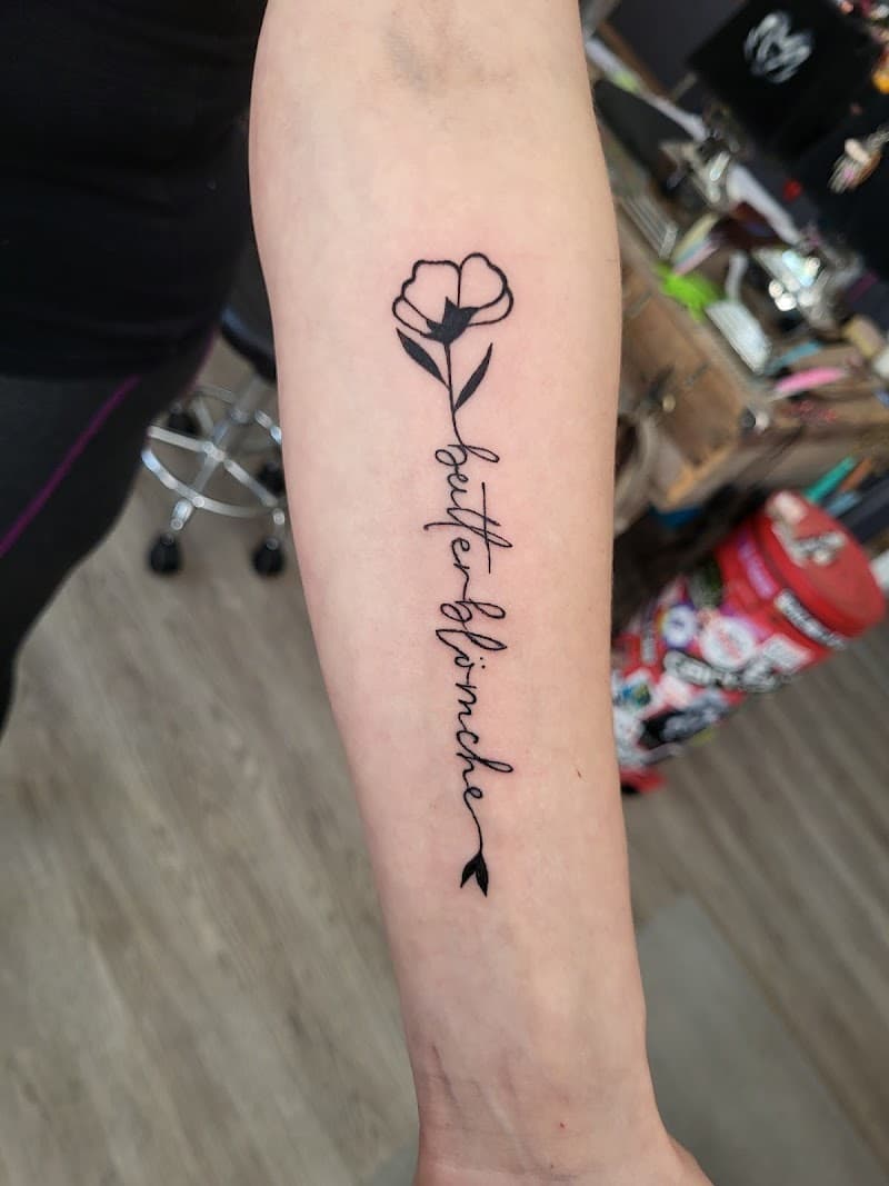 Fineline bloem met 'butterblümchen' tekst op onderarm.