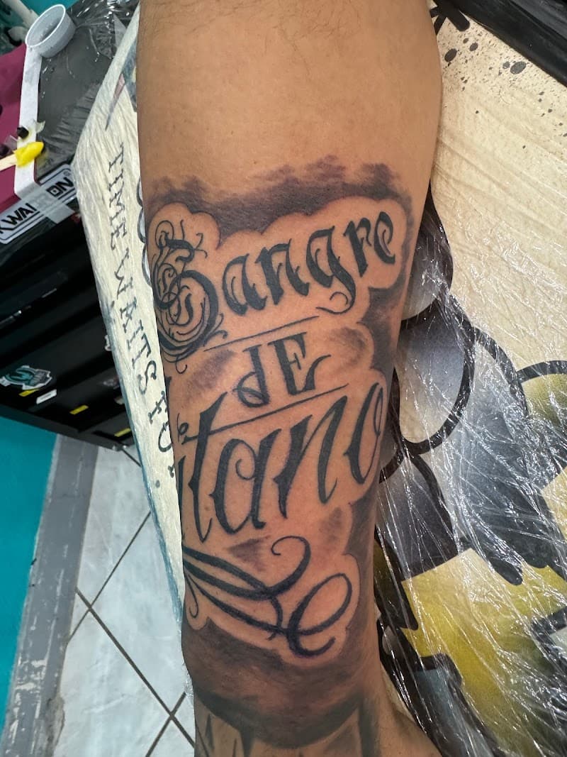 Grote 'Sangre de Gitano' lettering tattoo op onderbeen.