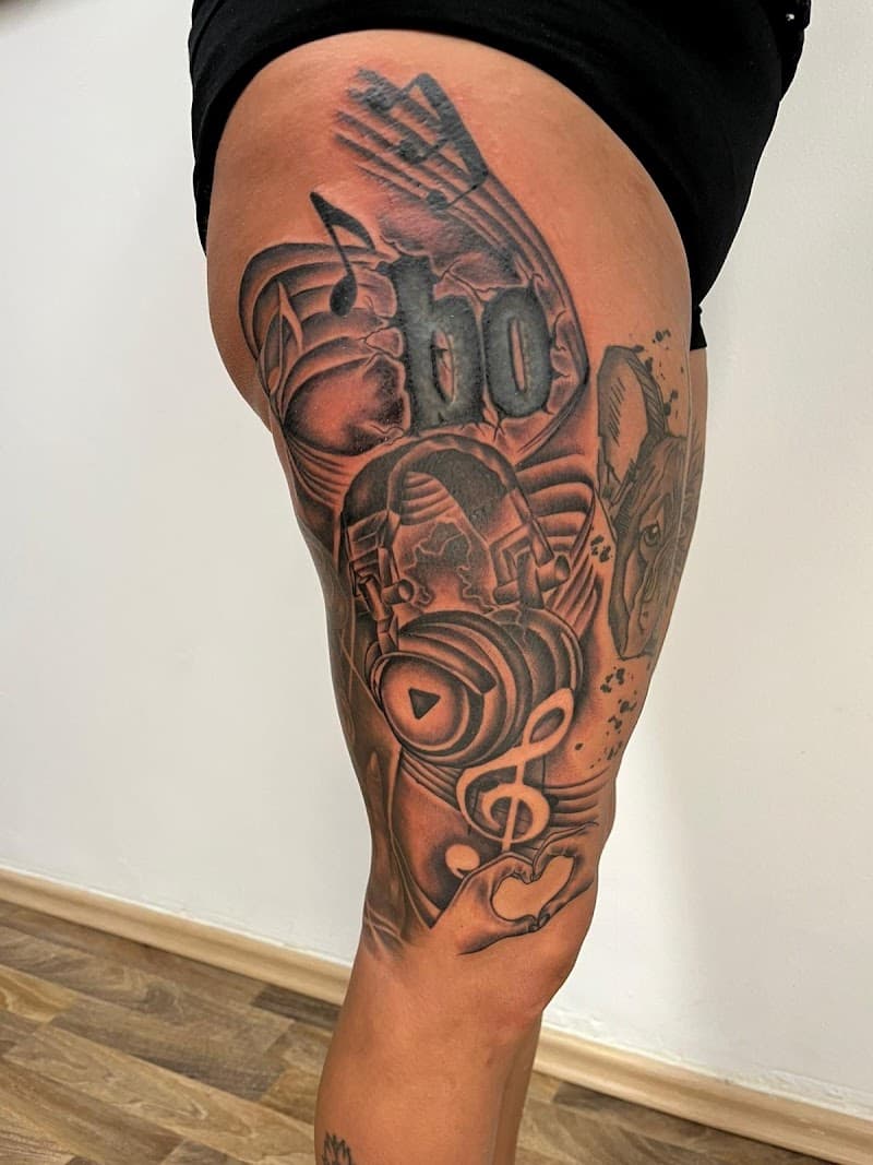 Grote zwart-grijze tattoo op bovenbeen met koptelefoon, muzieknoten en hart.