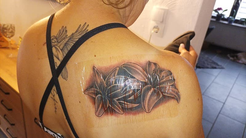 Twee lelies en een kolibrie op de schouder en bovenrug.