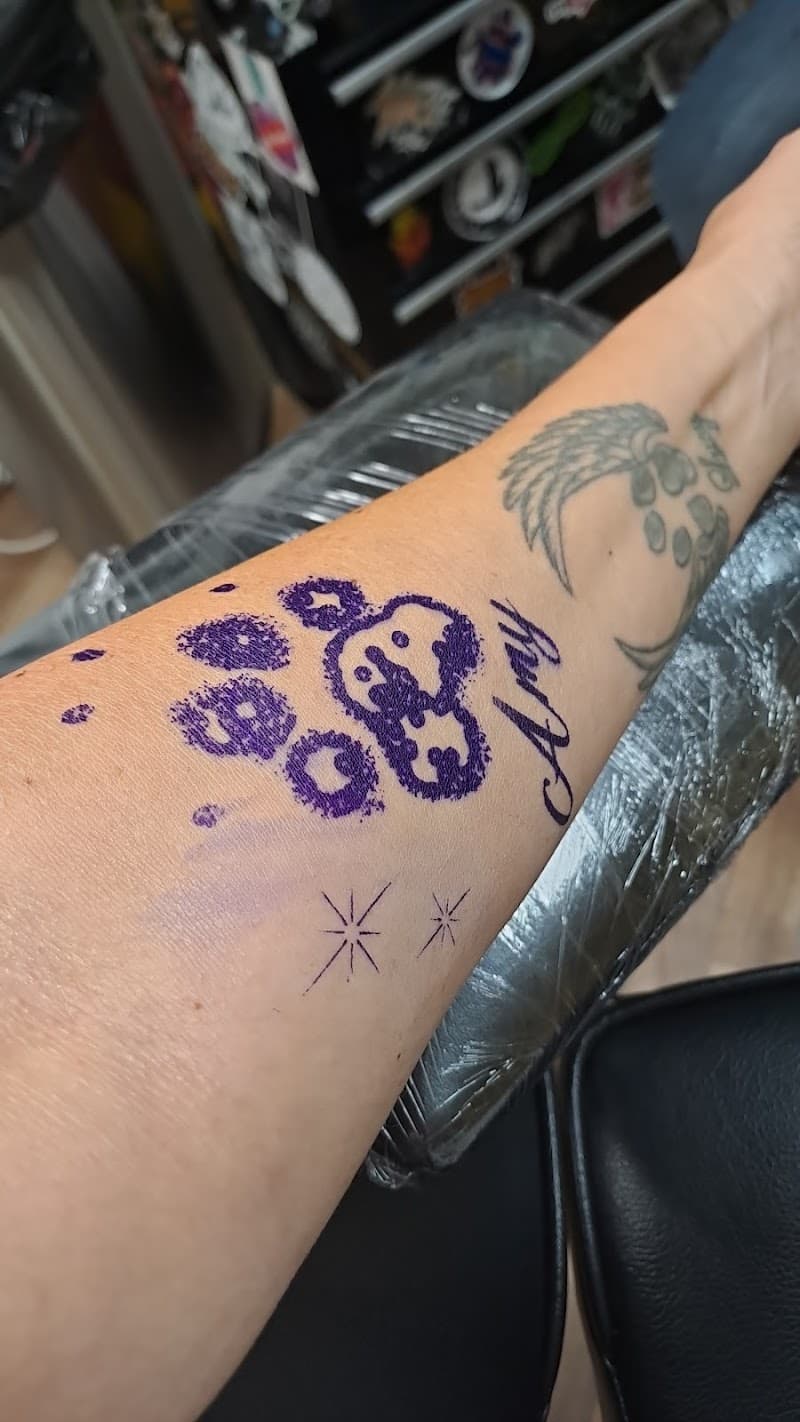 Paarse pootafdruk met gezicht, naam 'Amy' en sterretjes op onderarm.