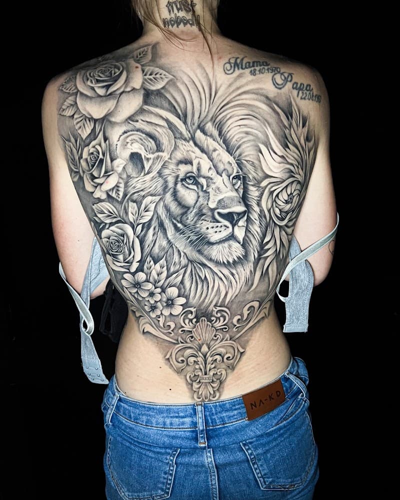 Grote zwart-wit rugtattoo van een leeuw met rozen en een ornament.