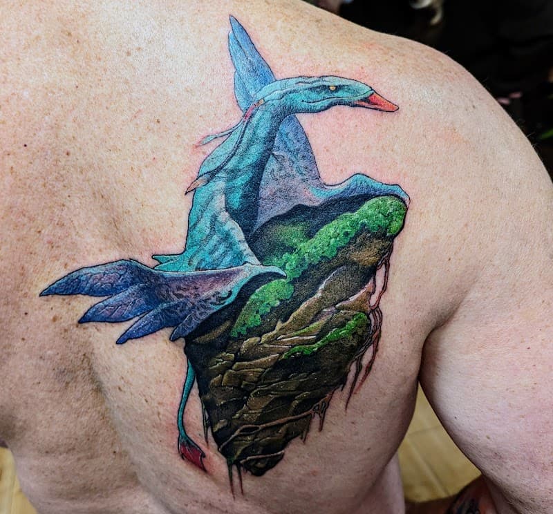 Blauwe draak op een zwevend rotseiland op de schouder.