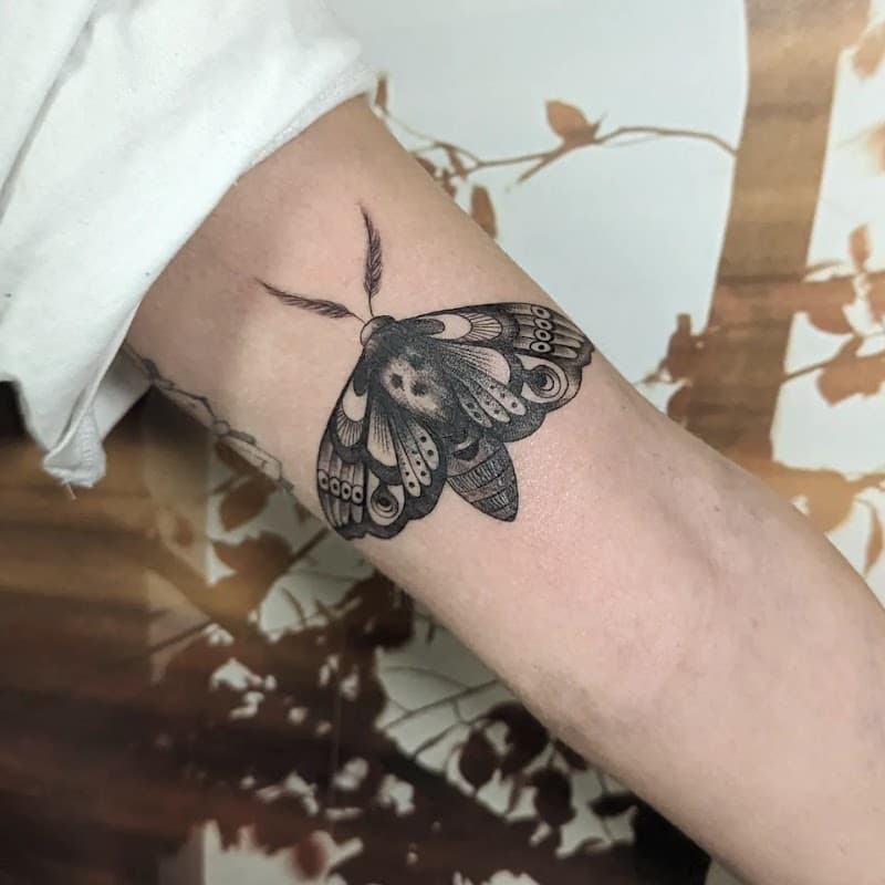 Gedetailleerde dotwork mot tattoo op de binnenkant van de bovenarm.