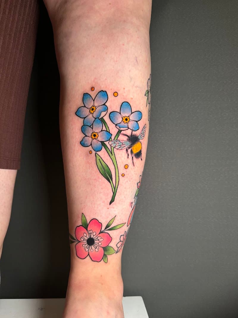 Vergeet-mij-nietjes met een hommel en een roze bloem op het onderbeen.