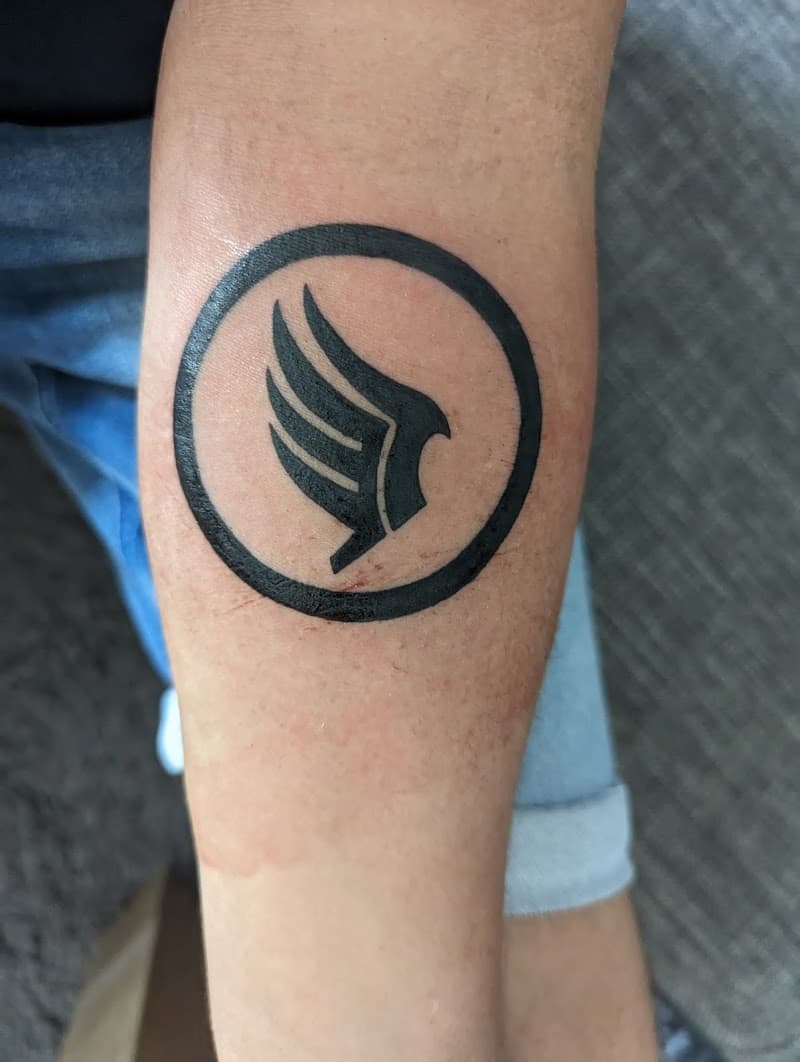 Zwarte Mass Effect Paragon symbool tattoo op onderarm.