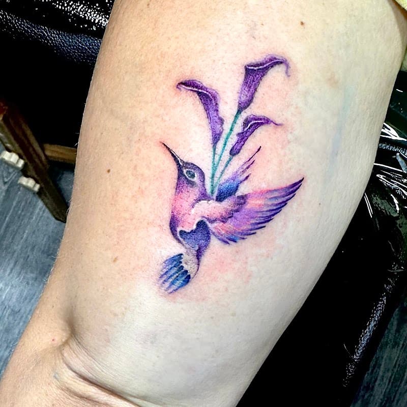 Paarse aquarel kolibrie met calla lelies op onderarm.