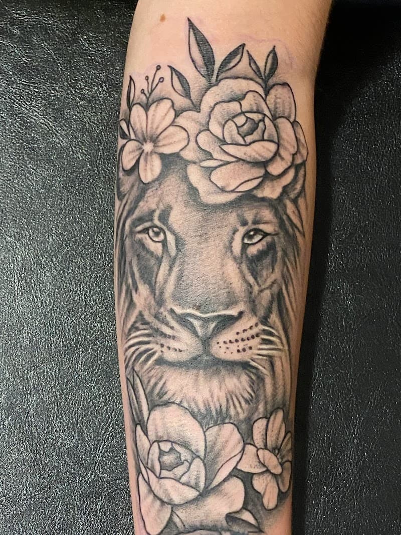 Blackwork leeuwin met bloemenkroon op onderarm.
