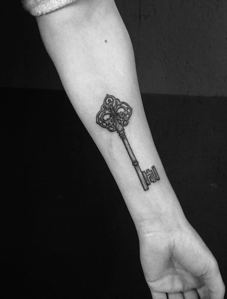 Gedetailleerde vintage sleutel tattoo op de onderarm.