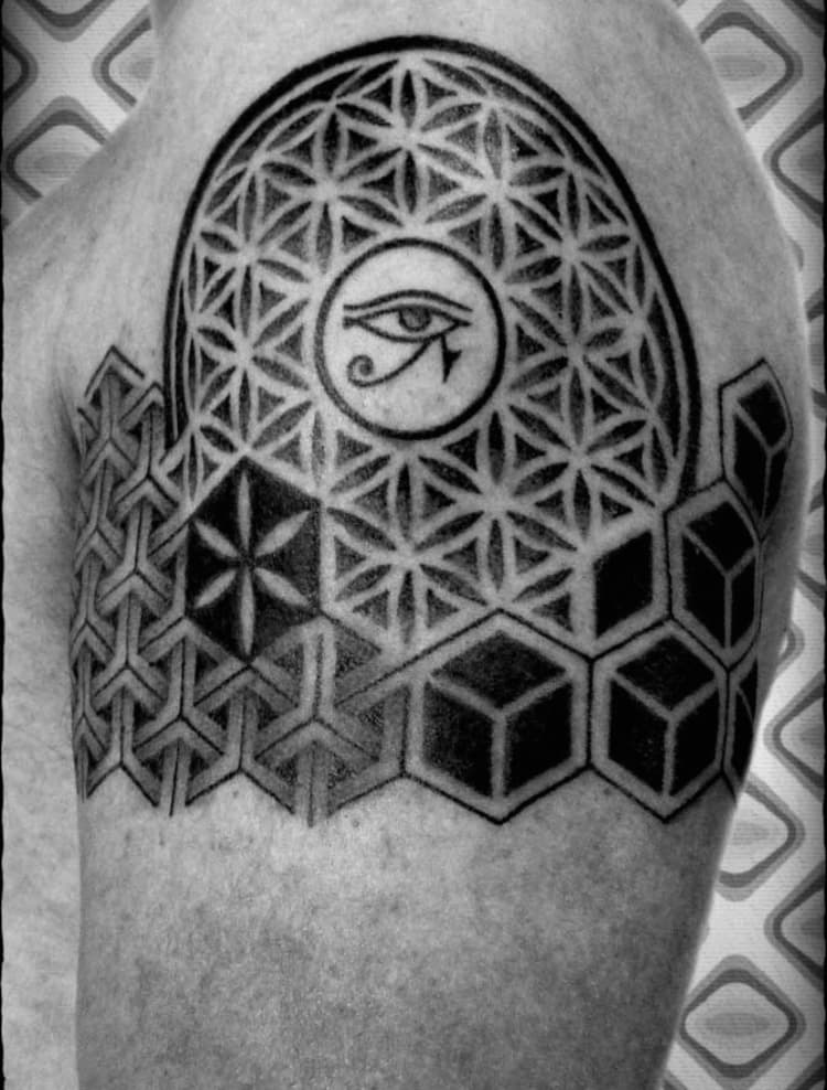 Geometrische tattoo met Flower of Life, Oog van Horus en kubussen op bovenarm.