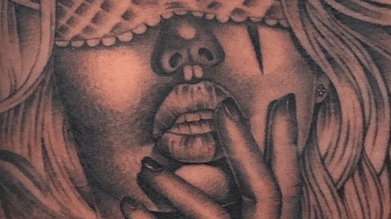 Close-up van een Chicano tattoo van een vrouw met masker en hand voor mond.