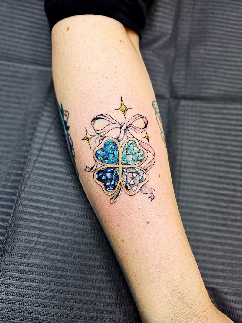 Kleurrijke edelsteen klavertje vier met strik op onderbeen.