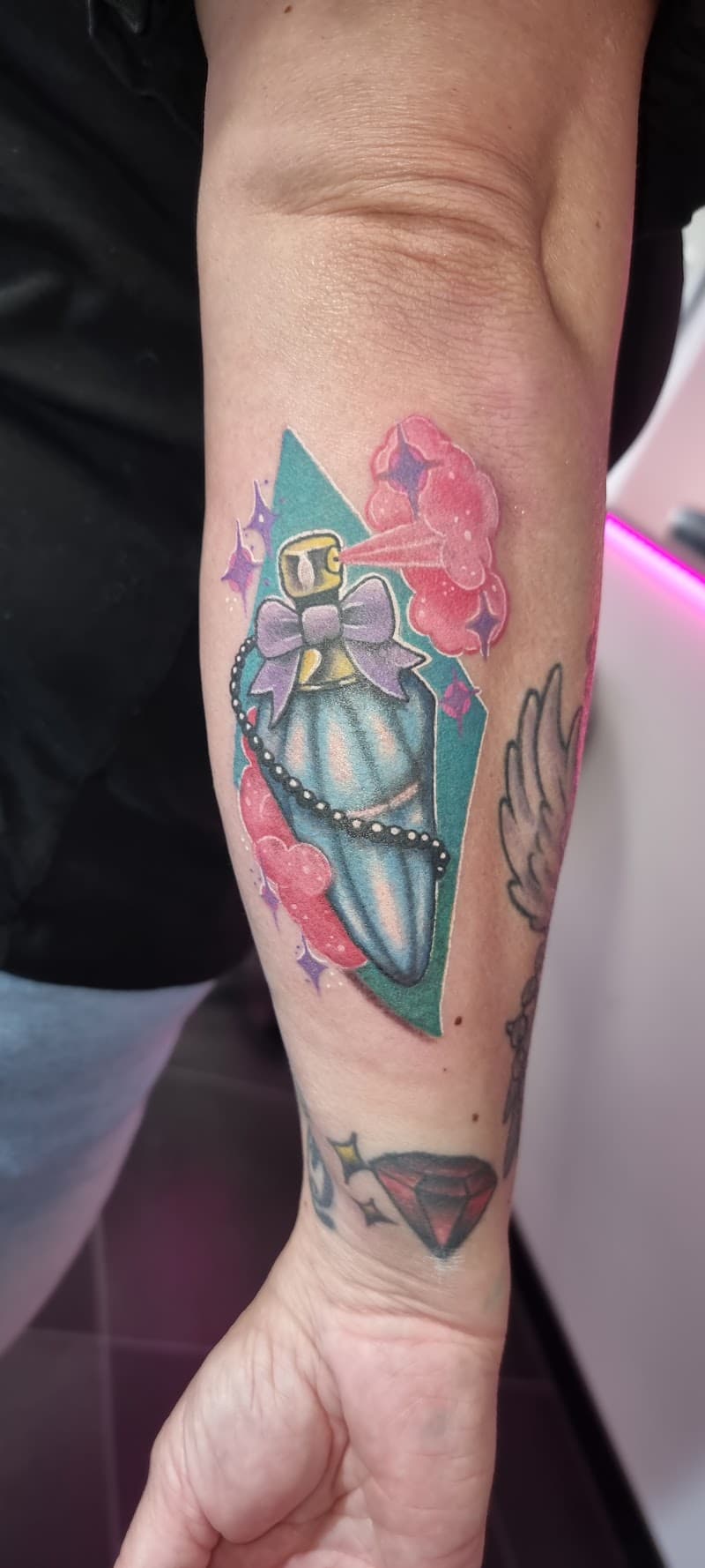 Kleurrijke parfumfles in een doodskistvorm met roze rook en sterren.