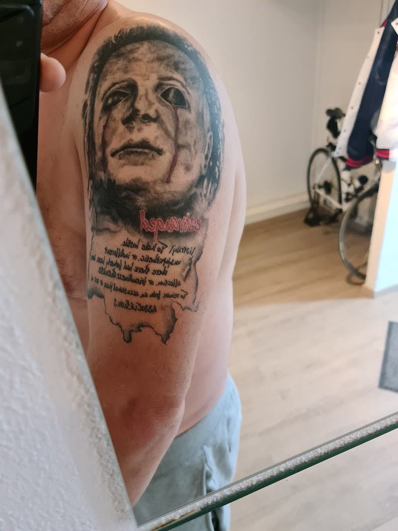 Realistisch portret van Michael Myers met tekst op de bovenarm.
