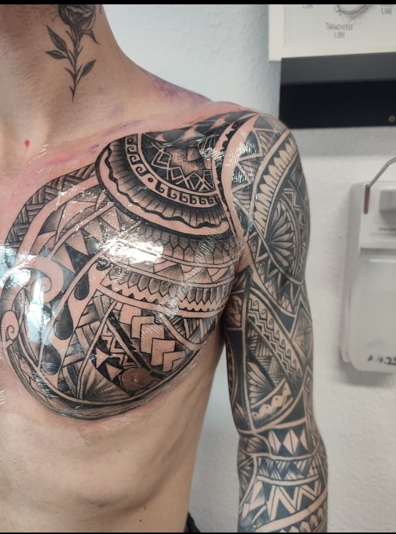 Grote Polynesische tribal tattoo op borst en arm, plus kleine roos in nek.