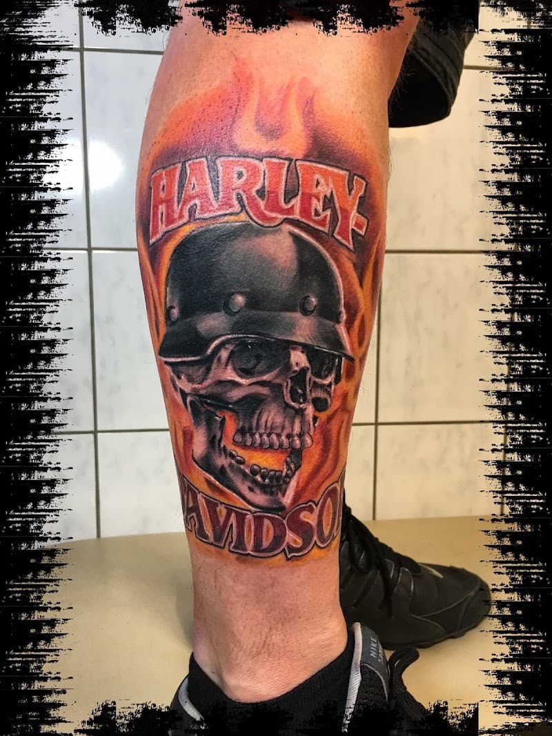 Schedel met helm, vlammen en Harley Davidson tekst op onderbeen.