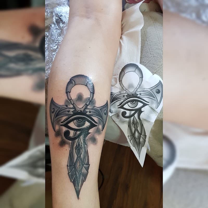 Zwart-wit tattoo van een Ankh kruis met het Oog van Horus op het onderbeen.