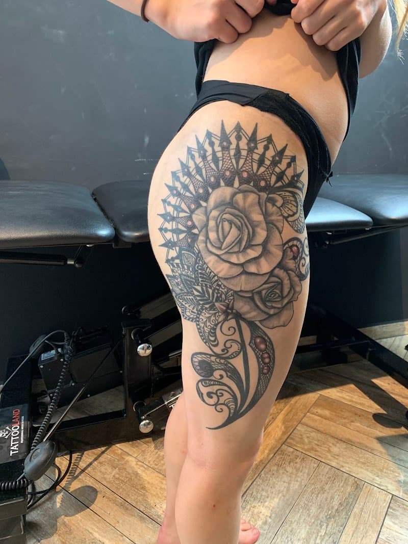 Grote zwart-wit tattoo op bovenbeen met rozen en mandala/kant patroon.