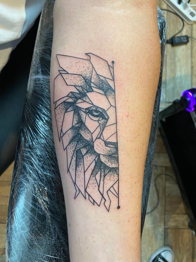 Geometrische leeuwenkop tattoo op onderarm.