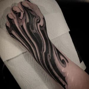 Zwart-wit abstracte vlammen of golven tattoo op hand en onderarm.