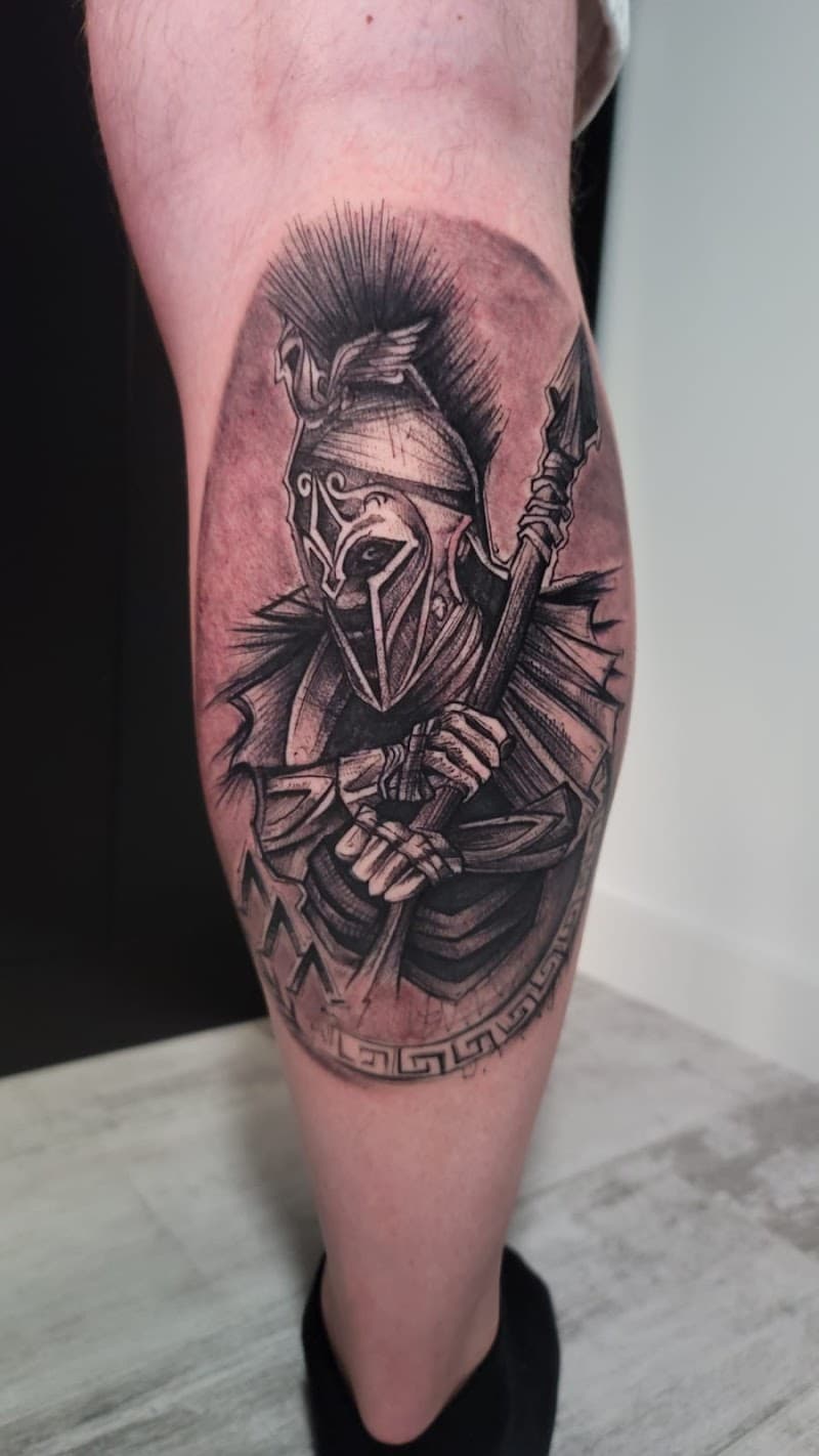 Blackwork tattoo van een Spartaanse krijger met speer en helm op het onderbeen.