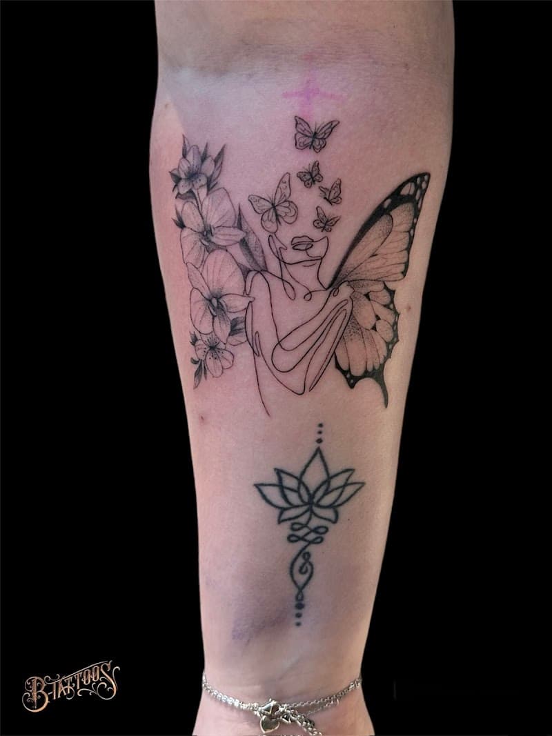 Fineline vrouw met vlindervleugels, bloemen en unalome lotus op onderarm.