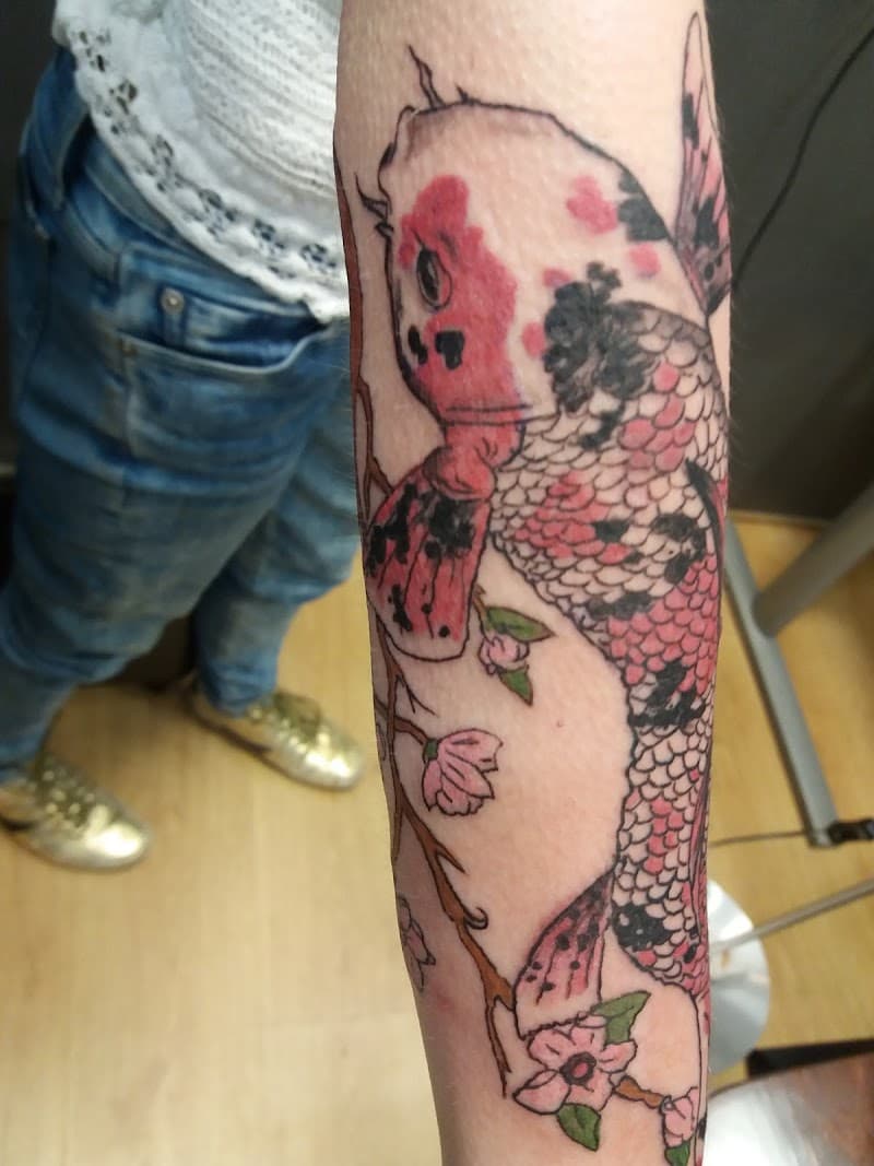 Kleurrijke Japanse koi karper met kersenbloesem op onderarm.