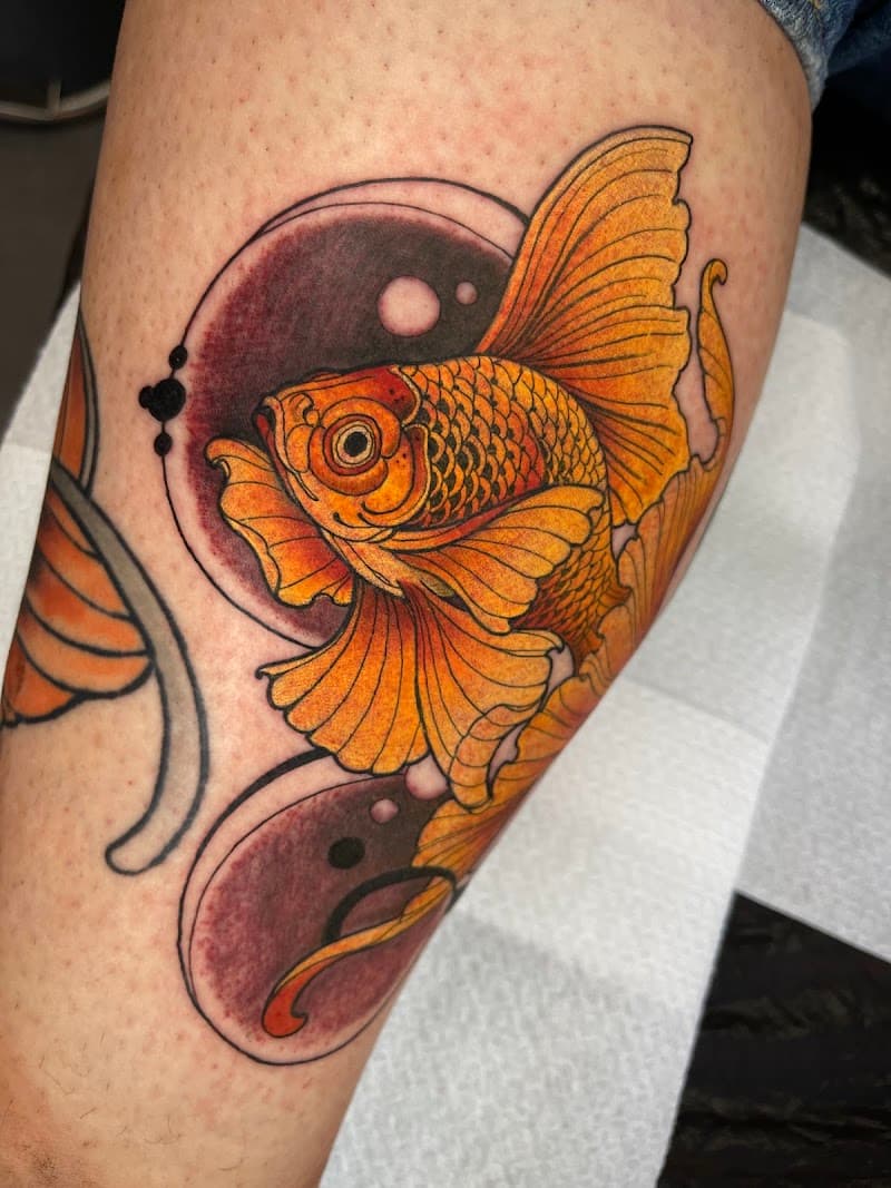 Neo-traditionele goudvis tattoo met cirkels op onderbeen.